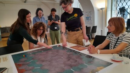 People around a table playing a board game on digital archiving for citizens.
